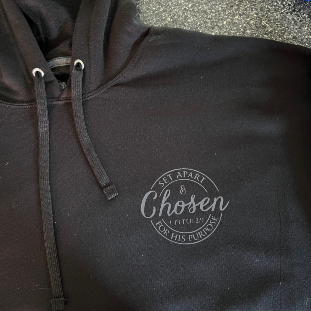 A display of personalized sweatshirts featuring Christian motifs and quotes, by Creative Adventure Co.